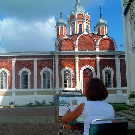 Woman sitting and painting a church